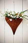 Spring wall decoration with snowdrops in heart-shaped vessel