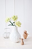 Grüne Nelke in moderner, weißer Vase mit kleinen Voegeln