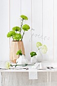 Verschiedene Vasen mit Chrysanthemen, Bartnelken, Nelken und Scheeball; Draht-Schriftzug 'Green' an der Wand