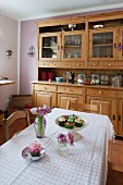 Dining table with red and white checked tablecloth in front of solid wood dresser