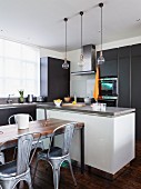 Dining area with retro metal chairs in front of free-standing counter in open-plan fitted kitchen with dark grey cabinet fronts
