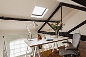 Desk on wooden trestles and office chair on gallery with partially exposed wooden structure
