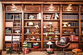 Antique-style, fitted shelves of antiquarian books, cake stands and cake platters