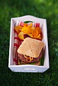 A hamburger with vegetable crisps for a picnic