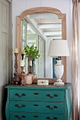 Shabby chic lamp, carved candlesticks and mirror on vintage chest of drawers painted turquoise