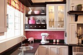 Black and white fitted kitchen with striped Roman blind and pink blackboard splashback