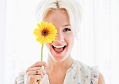 Portrait of blonde woman holding yellow flower