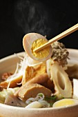 Chopsticks picking up egg from a bowl of noodle soup (Japan)