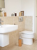 Waschbecken und WC an Vormauerung mit sandfarbenen Fliesen in modernem Bad