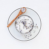 A pot of lavender sugar on a saucer with a spoon