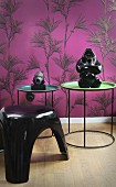 Sculptures on tray tables and retro plastic stool in front of mauve wallpaper