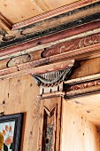 Kapitellornament auf Pilaster und florale Verzierungen als Teil der kunstvollen Holzvertäfelung in einem italienischen Chalet