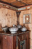 Pewter tureens on old farmhouse cupboard in wood-panelled dining room