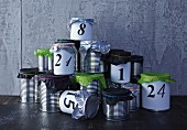 Hand-crafted Advent calendar made from tin cans with tissue paper lids