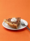 A slice of pecan pie with a dollop of cream