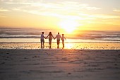 Familie geht händehaltend am Strand entlang (Cape Town, Südafrika)