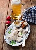White sausage with mustard, pretzel, radishes and beer