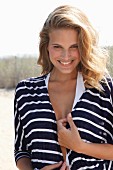 A young blonde woman wearing a blue-and-white stripped jacket over a swimsuit