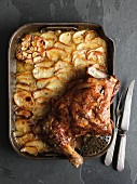 Slow-roasted shoulder of lamb on a bed of sliced potatoes with garlic