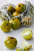 Green tomatoes, some in a net shopping bag
