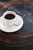 Cup of coffee on saucer on tree stump with growth rings
