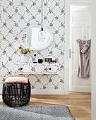 A make-up table and a wall creating a graphic element – Scandinavian, vintage-style patterned wallpaper on both the wall and the make-up table with a black wicker stool in front of it