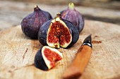 Fresh red figs on a chopping board with a knife