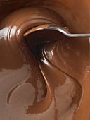 A spoon being used to stir melted milk chocolate (close-up)