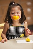 A little girl with Down Syndrome eating an orange