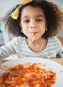 An African American girl eating spaghetti