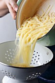 Spaghetti being drained into a colander