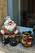 French garden gnome and vase decorated with applied ceramic flowers on windowsill