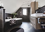 An elegant designer bathroom under a vaulted roof in various brown tones with a bathtub at an angle in the room