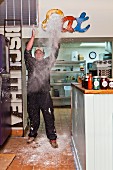 A chef in a restaurant throwing flour in the air