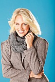 A young blonde woman wearing a taupe blazer and a matching loop scarf