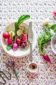 Various different types of radishes on a plate with a knife