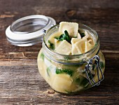 A jar of ravioli soup with spinach