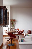 Brown leather swivel chairs and table in window bay in hotel with parquet flooring and white armchairs in foreground