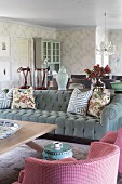 Armchair with pink and white checked cover and grey velvet sofa with scatter cushions around coffee table in romantic, elegant, country-house interior