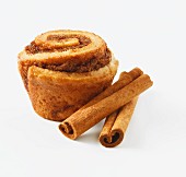 A cinnamon roll and cinnamon sticks