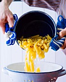 Pasta being drained into a colander
