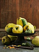 Quinces with leaves in a bowl in front of a wooden wall