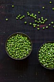 Peas in two bowls and spread over a wooden surface