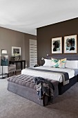Elegantes Schlafzimmer in Brauntönen - gepolsterte Bank an Bettende des Doppelbettes, an dunkelbrauner Wand gerahmte Bilder