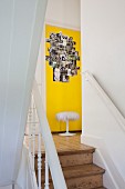 Staircase in old, Scandinavian house with view of photo collage on yellow-painted wall
