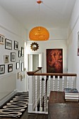 Orangefarbene Hängeleuchte über Treppenaufgang im Gang, mit weisser Holzbalustrade, an Wand Bildersammlung