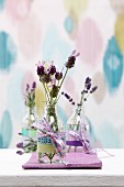 Sprigs of lavender in glass bottles decorated with ribbons and washi tape decorating table