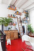 Red-painted wooden floor on gallery; wooden bookshelves on wall, classic rocking chair with white animal-skin rug