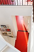 View down onto red-painted wooden floor in open-plan stairwell