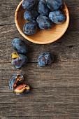 Fresh plums in a wooden bowl and next to it